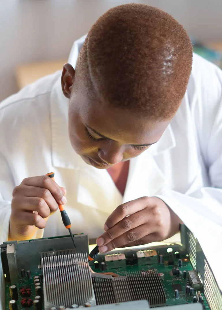 Karim, artisan informatique KDL TECH aux Abymes, réparant une carte électronique